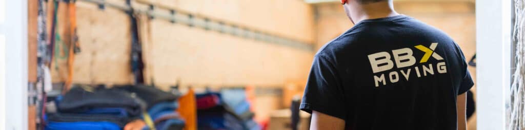 BBX Moving | Office Movers – Burnaby - A person wearing a "BBX Moving" t shirt stands near a stack of moving blankets inside a moving truck, ready to assist as expert office movers in Richmond. A person wearing a "BBX Moving" t shirt stands near a stack of moving blankets inside a moving truck, ready to assist as expert office movers in Richmond.