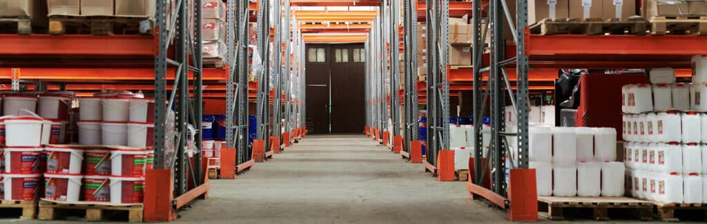 BBX Moving | Warehouse Movers – West Vancouver - Warehouse interior in Richmond, with shelves stocked with containers, boxes, and barrels, arranged in rows along a central aisle leading to a closed door—ideal for Warehouse Movers handling organized inventory. Warehouse interior in Richmond, with shelves stocked with containers, boxes, and barrels, arranged in rows along a central aisle leading to a closed door—ideal for Warehouse Movers handling organized inventory.